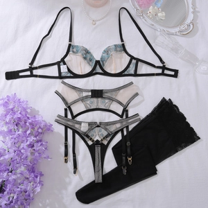 Dettaglio del set di lingerie in pizzo nero con ricami floreali blu e calze abbinate