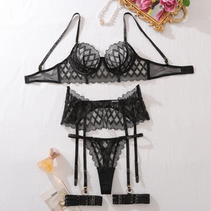 Detailed flat lay of black lace lingerie set with gold hardware and pearl accessories