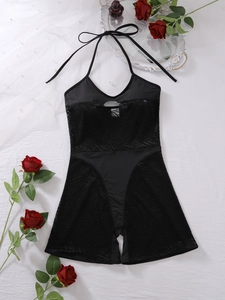 Detailed view of black halter neck mesh bodysuit with hollow-out lace design on white fabric