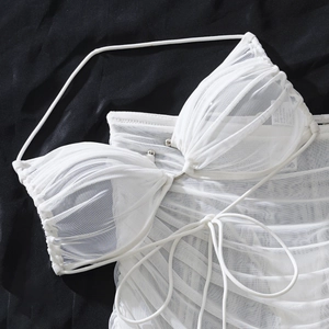 Dettaglio del top bikini in rete bianca con texture arricciata e perline metalliche