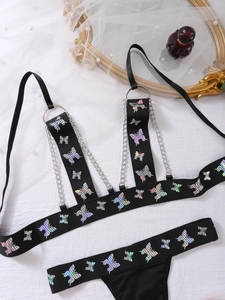 Detail von Laser-Schmetterlings-Print Dessous mit Silberketten und Ringen auf weißem Stoff