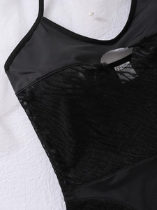 Detail of black lace-up mesh patchwork bodysuit with sheer net fabric and elastic stitching
