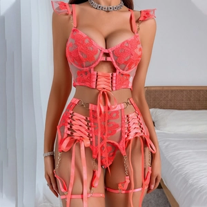 Dettaglio del reggiseno in pizzo rosa corallo con ricamo e reggicalze a incrocio