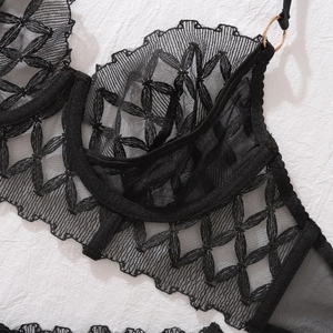 Detail of black lace bra with floral embroidery, underwire support and gold metal ring