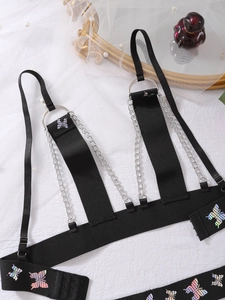 Detail eines gotischen schwarzen Harness-BHs mit Schmetterlingsdruck und Silberketten