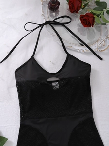 Macro detail of black lace bodysuit with halter neck, mesh cutout, and floral accents