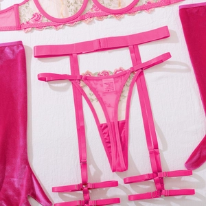Dettaglio dell'intimo ricamato floreale rosa con rete velata e guanti di velluto