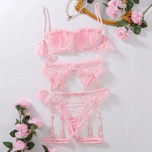 Dettaglio flat lay di un set lingerie in pizzo rosa con volant e fibbie dorate