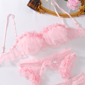 Dettaglio del set lingerie in pizzo rosa con volant su un tavolo strutturato