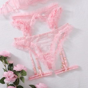 Dettaglio di completo lingerie in pizzo rosa con reggicalze a balze e fibbie dorate in metallo
