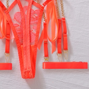 Dettaglio del reggicalze in pizzo arancione neon con catene in metallo dorato