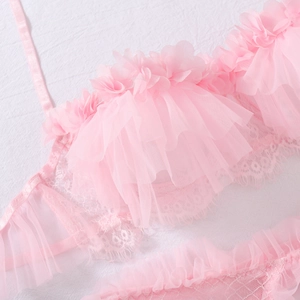 Dettaglio ravvicinato del set lingerie in pizzo rosa con bordi a balze e ricami delicati
