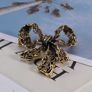 Macro detail of a vintage golden bow brooch with sparkling crystals on a magazine
