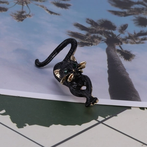 Detail of wild cat brooch with black matte enamel, gold edges and green stone eyes