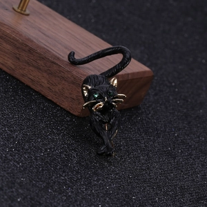 Detailed close-up of a black enamel cat brooch with green gemstone eyes and gold trim