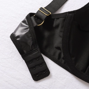 Detailaufnahme von schwarzer PU-Leder-Dessous mit goldener Metallkette und Hakenverschluss