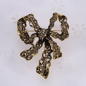 Detail of vintage bow brooch with amber rhinestones and intricate hollow carving texture