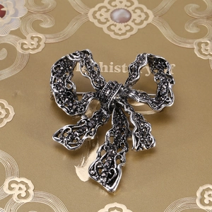 Close-up of vintage silver alloy bow brooch featuring intricate black rhinestone paving