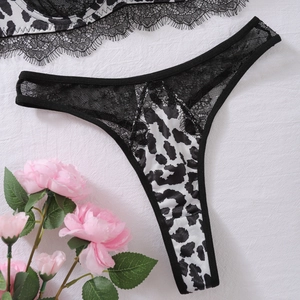 Detailed view of leopard print thong with intricate black floral lace and soft rose accents