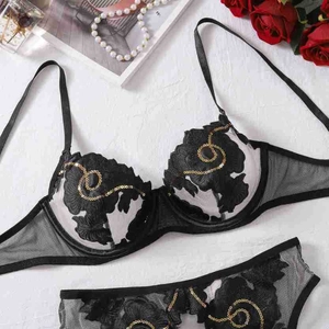 Detail der schwarzen floralen Stickerei-Dessous mit Goldpailletten auf weißem Stein