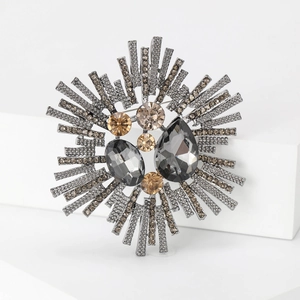 Vintage retro sunburst brooch with grey and champagne rhinestones on white display