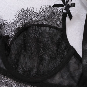 Detail of black lace bra featuring eyelash trim and small silk bow on the shoulder strap