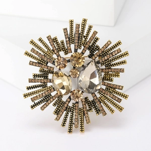 Macro detail of retro sunburst star brooch with amber crystals and gold plating