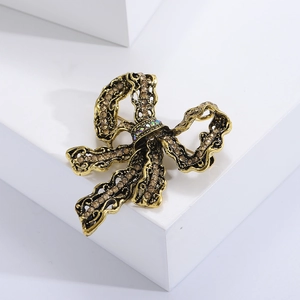 Vintage gold bowknot brooch with brown rhinestones displayed on a white block