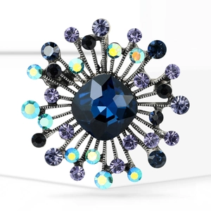 Detailed macro view of vintage sunburst brooch with deep blue octagonal center crystal