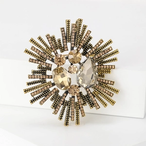 Vintage gold plated sunburst brooch with champagne gemstones on a white pedestal