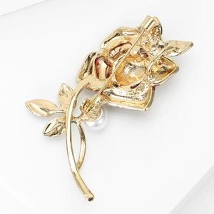 Detail view of gold rose brooch back showing safety pin closure and pearl accent