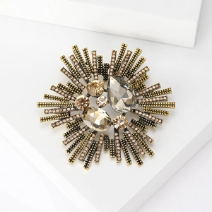 Detailed macro shot of vintage gold brooch with grey and amber crystals and small rhinestones