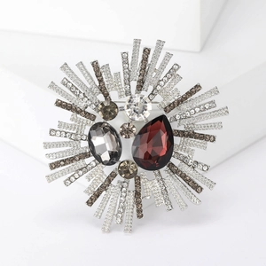 Detailed close-up of a vintage sunburst brooch with a red drop stone and grey crystals