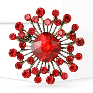 Macro shot of radial sunflower brooch with central red gemstone and gold alloy finish