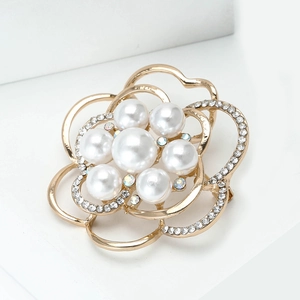 Détail d'une broche fleur évidée avec placage à l'or et perles blanches