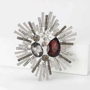 Vintage silver sunburst brooch with red teardrop crystal on white geometric stand