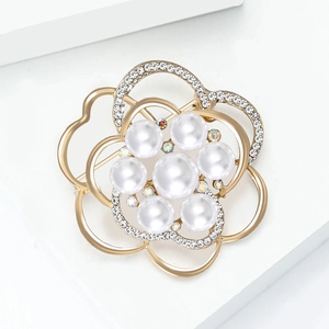 Vue détaillée d'une broche fleur dorée avec perles blanches et cristaux étincelants