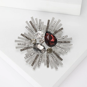 Detailed close-up of retro starburst brooch with red gemstone and silver plating