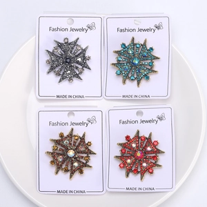 Macro view of vintage Maltese cross crystal brooches in four colors on a white display card