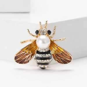 Détail macro de la broche abeille avec ailes en émail ambre et corps en perle blanche