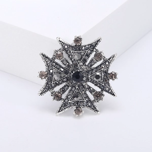 Vintage Maltese cross brooch with black rhinestones on a minimalist white background