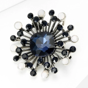Macro shot of vintage sunburst brooch featuring deep blue square crystal and silver alloy detail