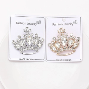 Detail of silver and gold crown brooches with inlaid rhinestones on a white plate