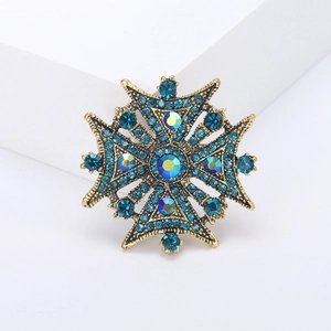 Detailed close-up of a vintage Byzantine style cross brooch with blue crystal rhinestones