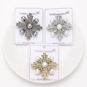 Détail de trois broches vintage en forme d'étoile avec perles et strass sur céramique