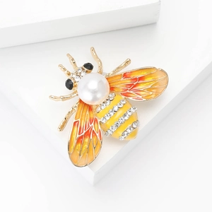 Broche abeille dorée avec perle blanche, ailes émaillées et strass sur blocs blancs