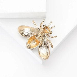 Vue détaillée de l'arrière d'une broche abeille dorée montrant la texture et le fermoir