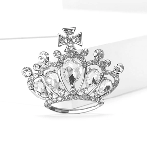 Close-up of crown brooch with teardrop crystal and cross detail on white block
