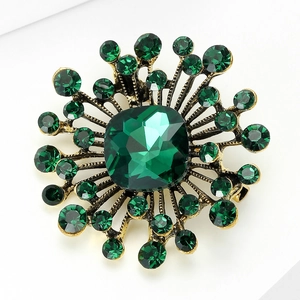 Macro detail of vintage sunflower brooch with deep green emerald stone and gold base