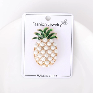 Detailed close-up of a pineapple pearl brooch with green enamel leaves on a display card